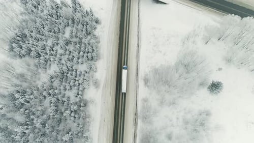 Truck drive along the road through the winter forest