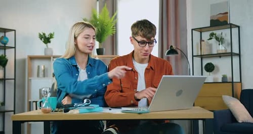 Jeune couple de travailleurs indépendants assis sur leur lieu de travail à la maison et travaillant dans le cadre d'une start-up conjointe
