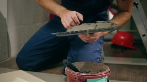 Person Applies Adhesive to Tiles with Trowel