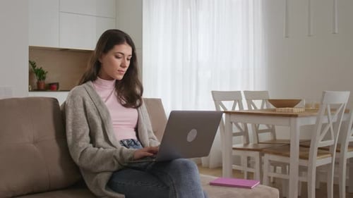Young Woman Using Laptop on Couch Indoors