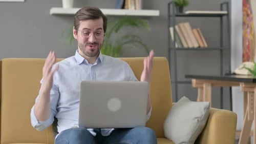 Man Waving During a Video Conference at Home