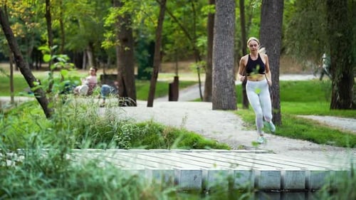 Athletic woman jogging across bridge in park