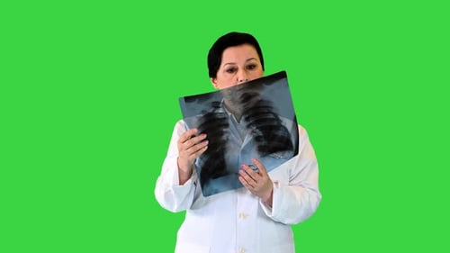 Reife Ärztin untersucht Röntgenaufnahme der Patientin auf einem Greenscreen-Chroma-Key
