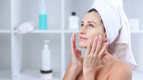 Smiling Young Woman Taking Off Cosmetic Mask and Massaging Face
