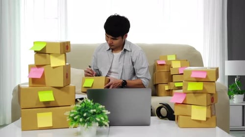 Young Adult Fulfilling Orders and Writing on Boxes