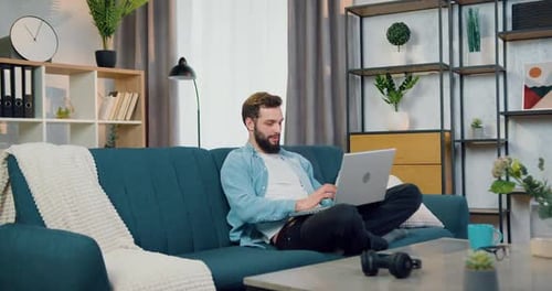 Man Relaxing at Home Typing on Laptop