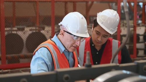Engineer teaching apprentice to use metal sheet stamping machine
