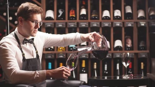 Sommelier qualifié versant le vin de la carafe dans un verre à vin
