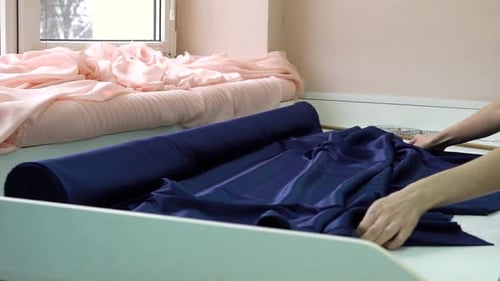 Female Hands Laying Roll of Blue Fabric on Table in Fashion Atelier