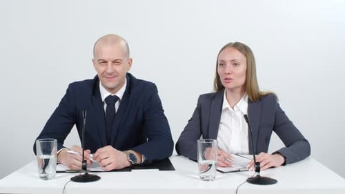 Professionals at Conference Table Speaking into Microphones