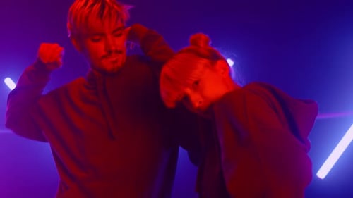 Stylish Couple Dancing Freestyle Together in Ultraviolet Backlit Close Up