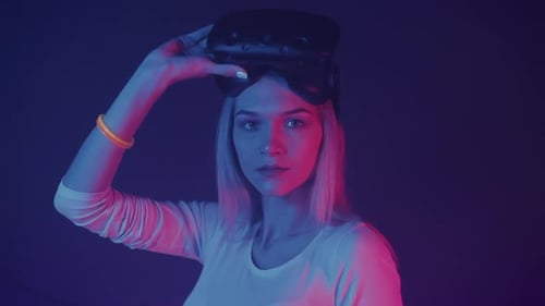 Woman Holding VR Headset in a Neon Lit Studio