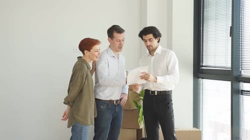 Confident Caucasian Real Estate Agent with House Model on Document is Talking to Clients About