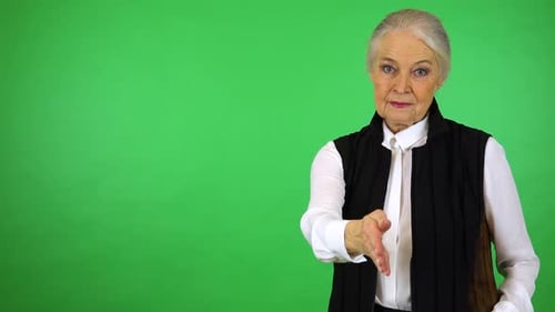 Uma mulher idosa estende a mão para a câmera - estúdio de tela verde