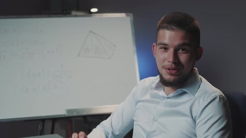 Young Adult Man Explaining Math Equations at Whiteboard