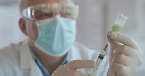 Doctor Hand Holds a Syringe and a Blue Vaccine Bottle at the Hospital. Health and Medical Concepts