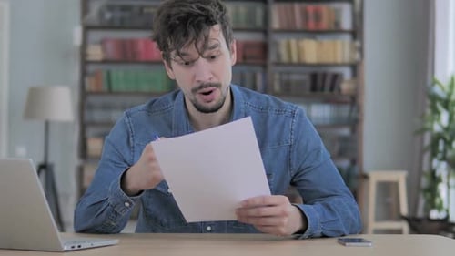 Excited Man Reading Good News at Desk