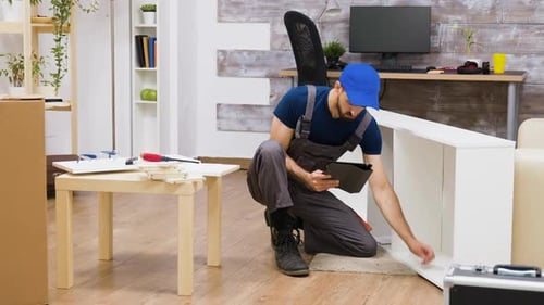 Travailleur utilisant la technologie moderne pour l'assemblage de meubles