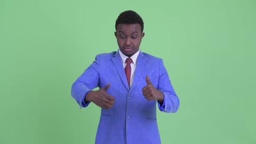 Confused Young African Businessman Choosing Between Thumbs Up and Giving Thumbs Down