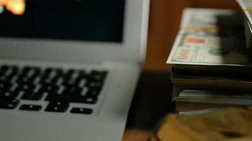 Laptop with Stack of Money on Desk
