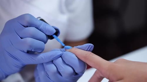 Close-up of Beautician Hands Making Blue Manicure for Client