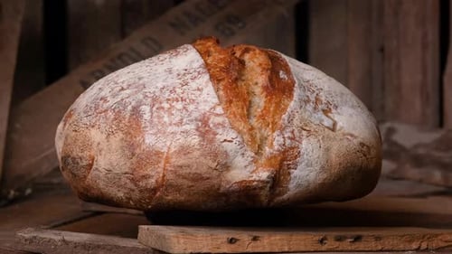 Whole Loaf Of Sourdough Bread Rotating On Wooden Table. - close up