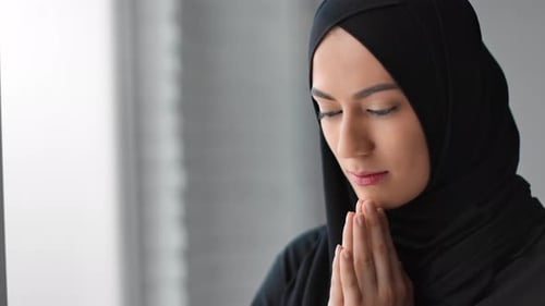 Nahaufnahme Muslimische Frau im schwarzen Hijab betet ruhigen Gesichtsausdruck