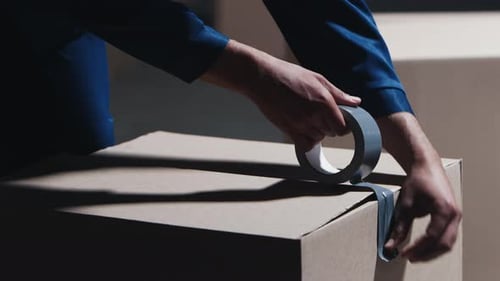 Packing Boxes with Construction Tape to Send the Order to Buyer From Warehouse