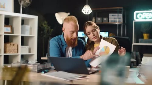 Friendly Man and Woman Presenting Project on Video Call in Dark Office.