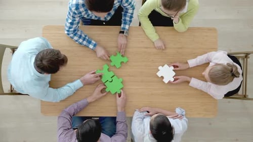 Team Collaboration Connecting Puzzle Pieces at Table