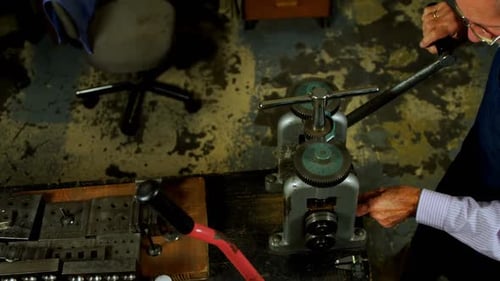 Goldsmith working on machine in workshop