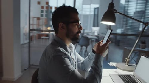 Middle Eastern Businessman Typing on Smartphone in Office
