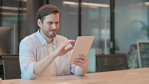 Frustrated Man Using Tablet in Modern Office