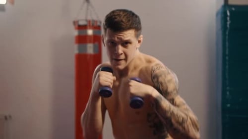 Muscular Man Boxing with Dumbbells at Gym