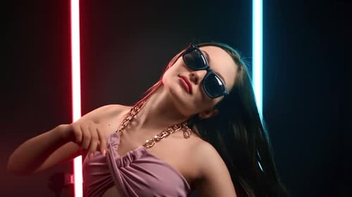 Portrait Fashion Lady in Sunglasses Dancing with Waving Hair at Illuminated Nightclub Party