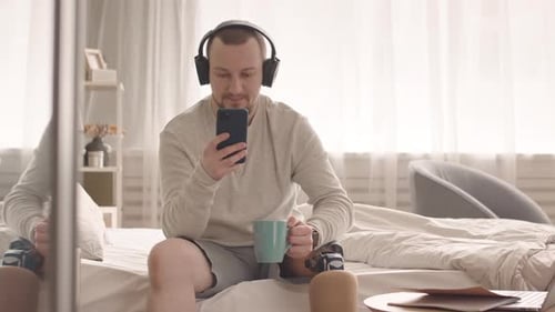 Man With Prosthetic Leg Listens With Headphones Indoors