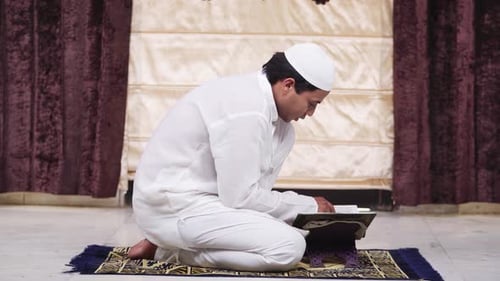 Man Kneels Reading Religious Book Indoors