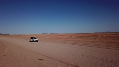 Conducción de automóviles en camino de grava en desierto aéreo