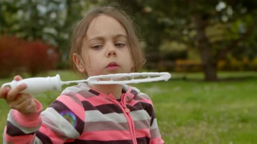 Girl Blowing Bubbles in a Sunny Park