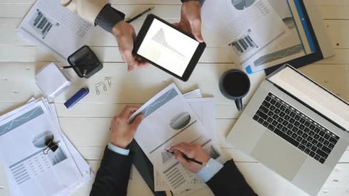 Top View Male Hands of Two Coworkers Checking Graphs with Statistics and Discussing Financial