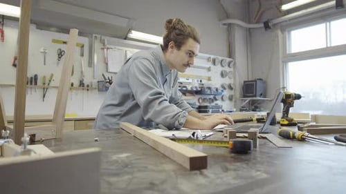 Furniture Maker Working with Laptop and Technical Drawings at Workshop