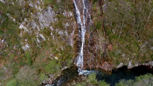 Aerial backward moving shot over waterfall of the Sor River at the viewpoint of Aguas Caídas, Manón,