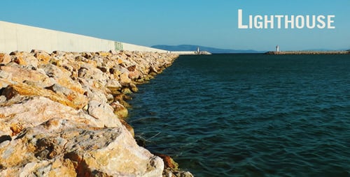 Rocky Coastline and Lighthouse Under Clear Blue Sky