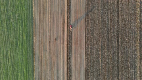 Aerial View of Agricultural Field Farmer in Tractor at Work Preparing Plowing Land