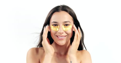 Woman Applying Gold Eye Patches to Face