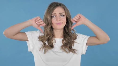 Young Girl Gesturing Thumbs Down Isolated on Blue Background