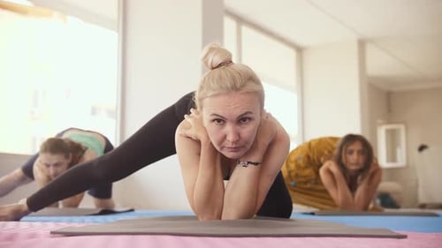 Yoga-Kurs im Studio Drei Frauen legen ihre Ellbogen auf den Boden und strecken ihr Bein bis zum
