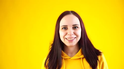 Close Up of Young Woman Smiling and Looking at Camera on Yellow Background