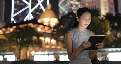 Woman Uses Tablet in City at Night