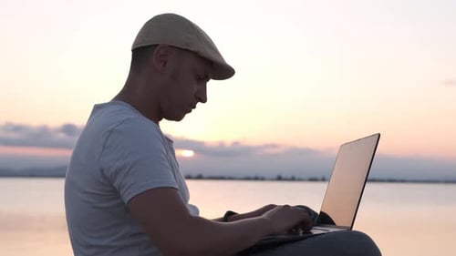 Young Adult Working on Laptop at Beach Sunset